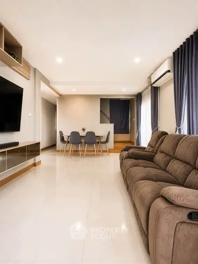 Spacious modern living room with plush sofa, dining area, and sleek TV setup.