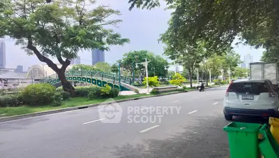 Charming urban street with lush greenery and modern architecture in the background.
