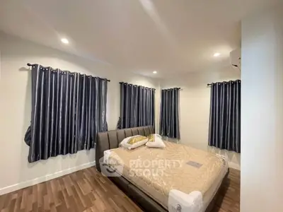 Spacious bedroom with elegant curtains and modern bed in a cozy setting.