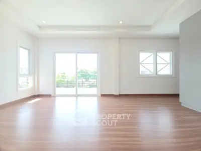 Spacious and bright living room with large windows and wooden flooring.