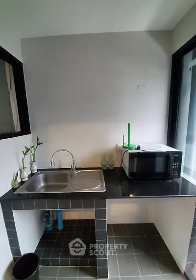 Modern kitchen with sleek countertop and built-in sink, featuring a microwave and minimalist decor.