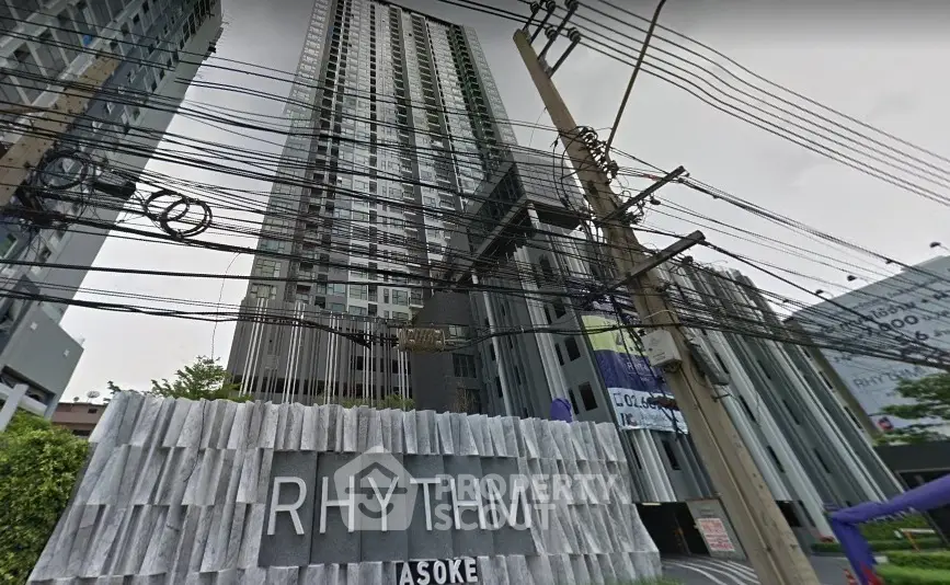 Modern high-rise building with sleek design and prominent signage in urban setting.