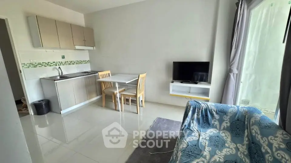 Cozy open-layout living area with kitchenette and TV, perfect for modern living.