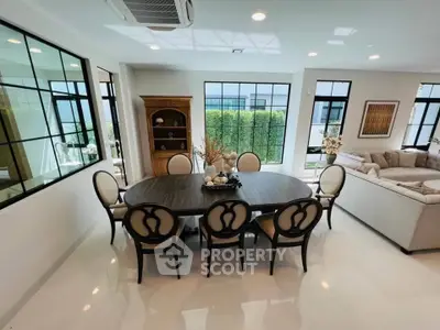 Elegant dining and living area with stylish furniture and large windows in a modern home.