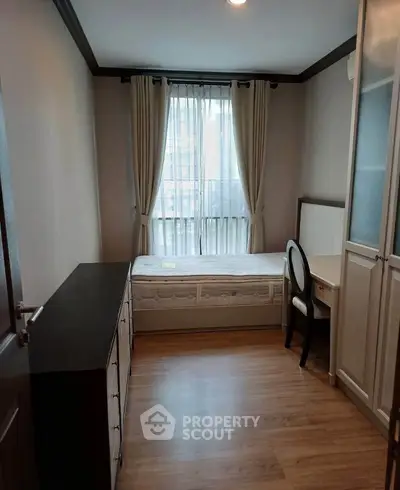 Cozy bedroom with natural light, wooden flooring, and elegant furnishings in a modern apartment.
