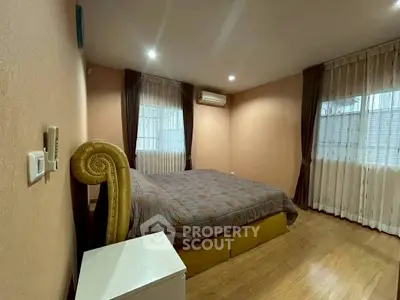 Cozy bedroom with elegant drapes and wooden flooring, featuring a comfortable bed and air conditioning.