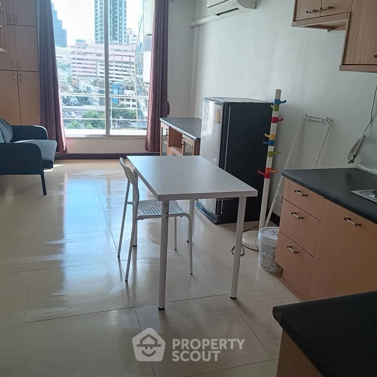 Bright studio apartment with city view, compact kitchen, and modern furnishings.