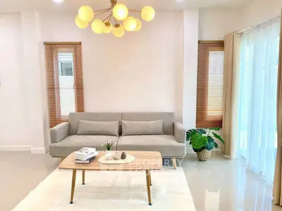 Modern living room with stylish sofa, elegant lighting, and natural light from large windows.