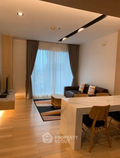 Modern living room with stylish furniture and large window, featuring a cozy seating area and elegant decor.