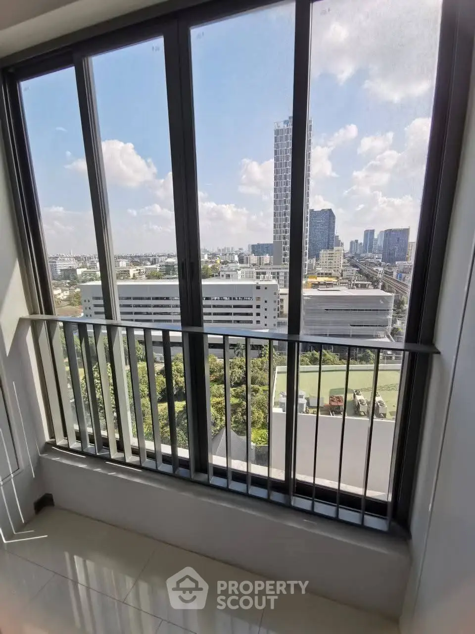 Stunning high-rise apartment view with expansive cityscape and lush greenery.