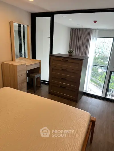 Modern bedroom with city view, featuring sleek furniture and large windows for natural light.