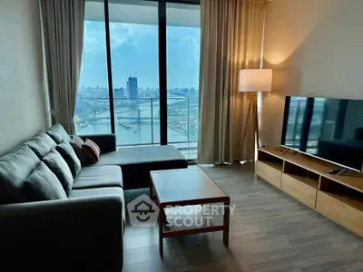 Modern living room with stunning city view, featuring a cozy sofa and sleek TV setup.
