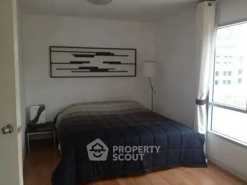 Cozy bedroom with modern decor and large window for natural light.