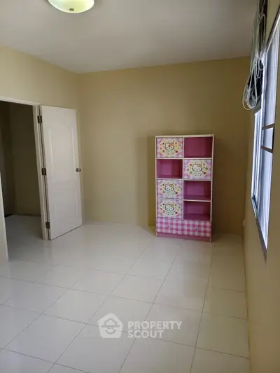 Bright empty room with white tiled floor and colorful storage unit, perfect for a child's bedroom.