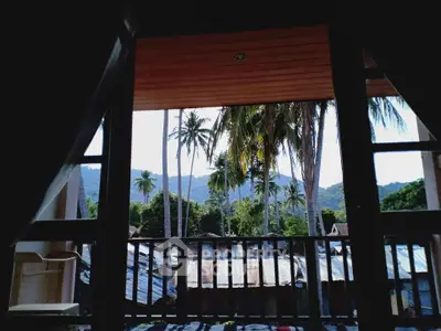 Stunning tropical view from a balcony with palm trees and mountains.