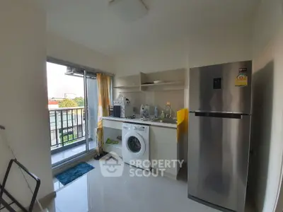 Modern kitchen with balcony view, featuring washing machine and fridge in a compact layout.