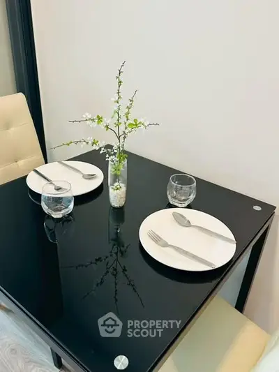 Elegant dining setup with black glass table and minimalist decor