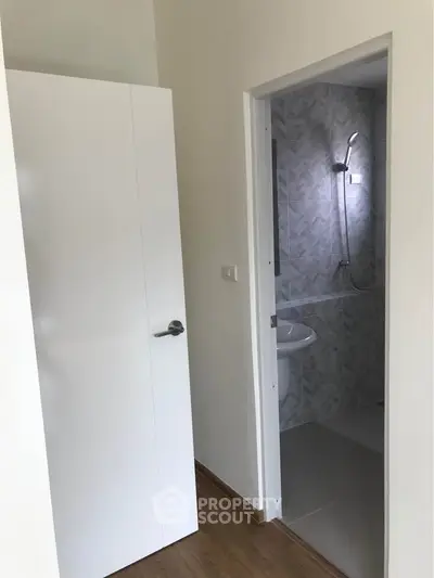 Modern bathroom entrance with sleek white door and stylish shower area.
