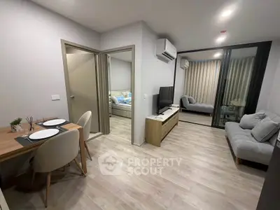 Modern open-plan living room with dining area and cozy bedroom in a stylish apartment.