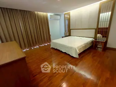 Spacious bedroom with wooden flooring and elegant decor in a modern apartment.
