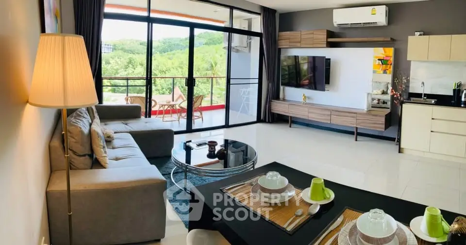 Spacious modern living room with open kitchen and balcony view, featuring stylish decor and natural light.