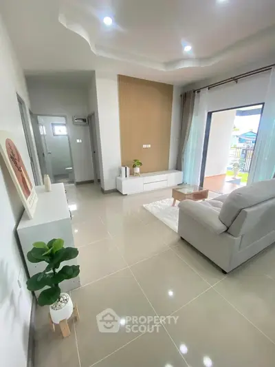 Spacious living room with modern decor and large windows opening to a balcony.