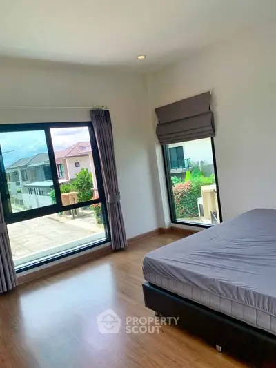 Spacious bedroom with large windows offering a beautiful view in a modern home.