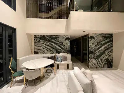 Luxurious modern living room with elegant marble accents and stylish furniture in a high-ceilinged space.