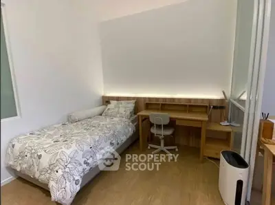 Cozy bedroom with modern desk and single bed, perfect for students or professionals.