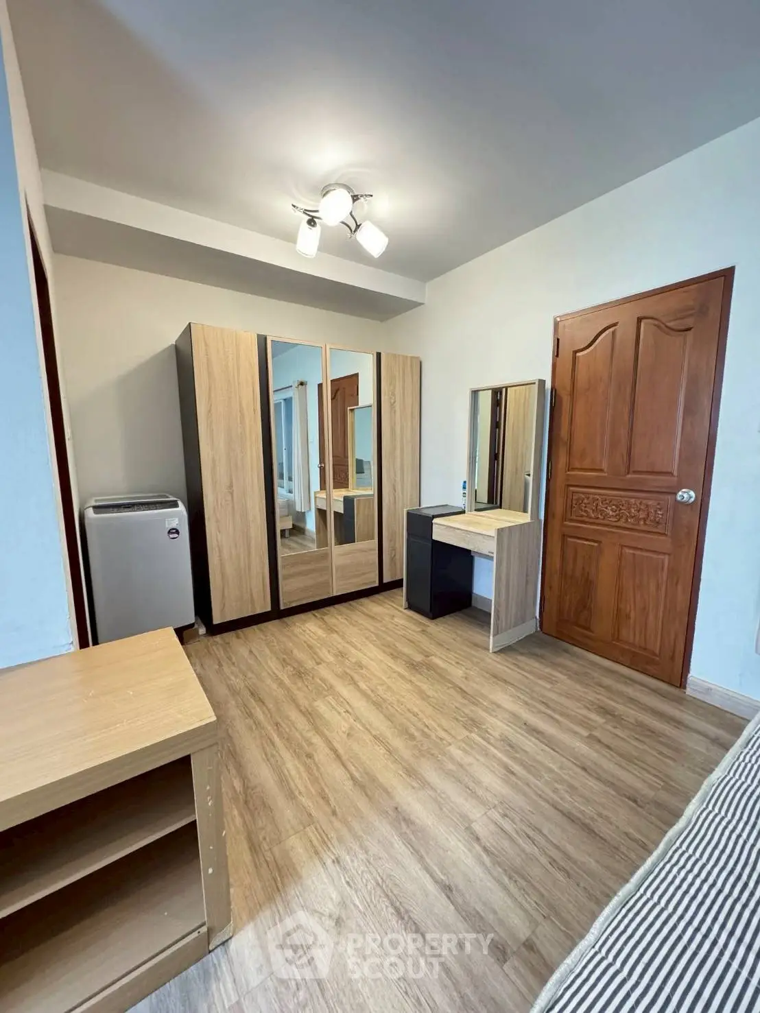 Spacious bedroom with modern wardrobe and wooden flooring