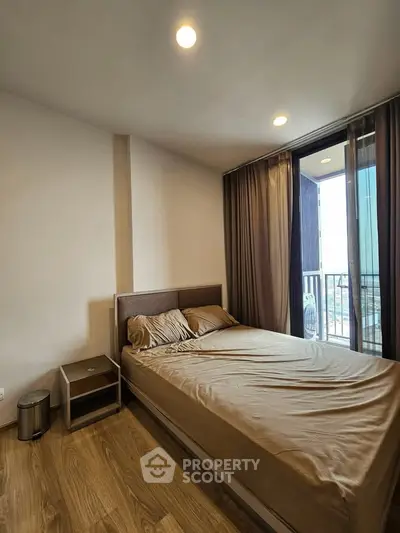 Modern bedroom with balcony access and wooden flooring in a stylish apartment.