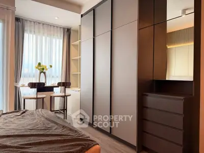 Modern bedroom with sleek wardrobe and cozy seating area by the window, perfect for relaxation.