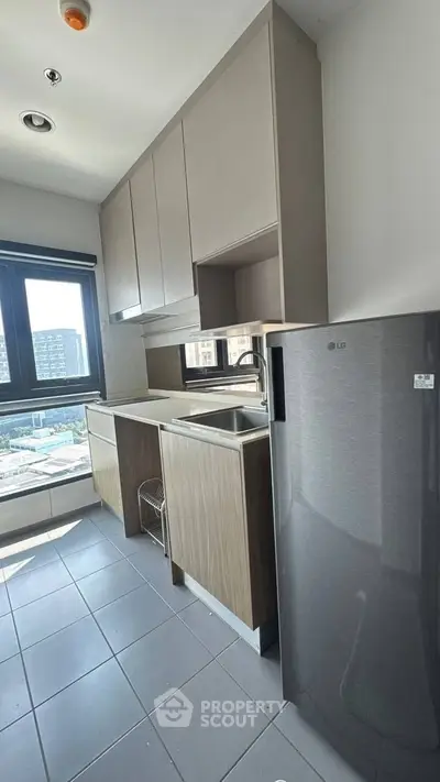 Modern kitchen with sleek cabinets and stainless steel fridge in a bright apartment.