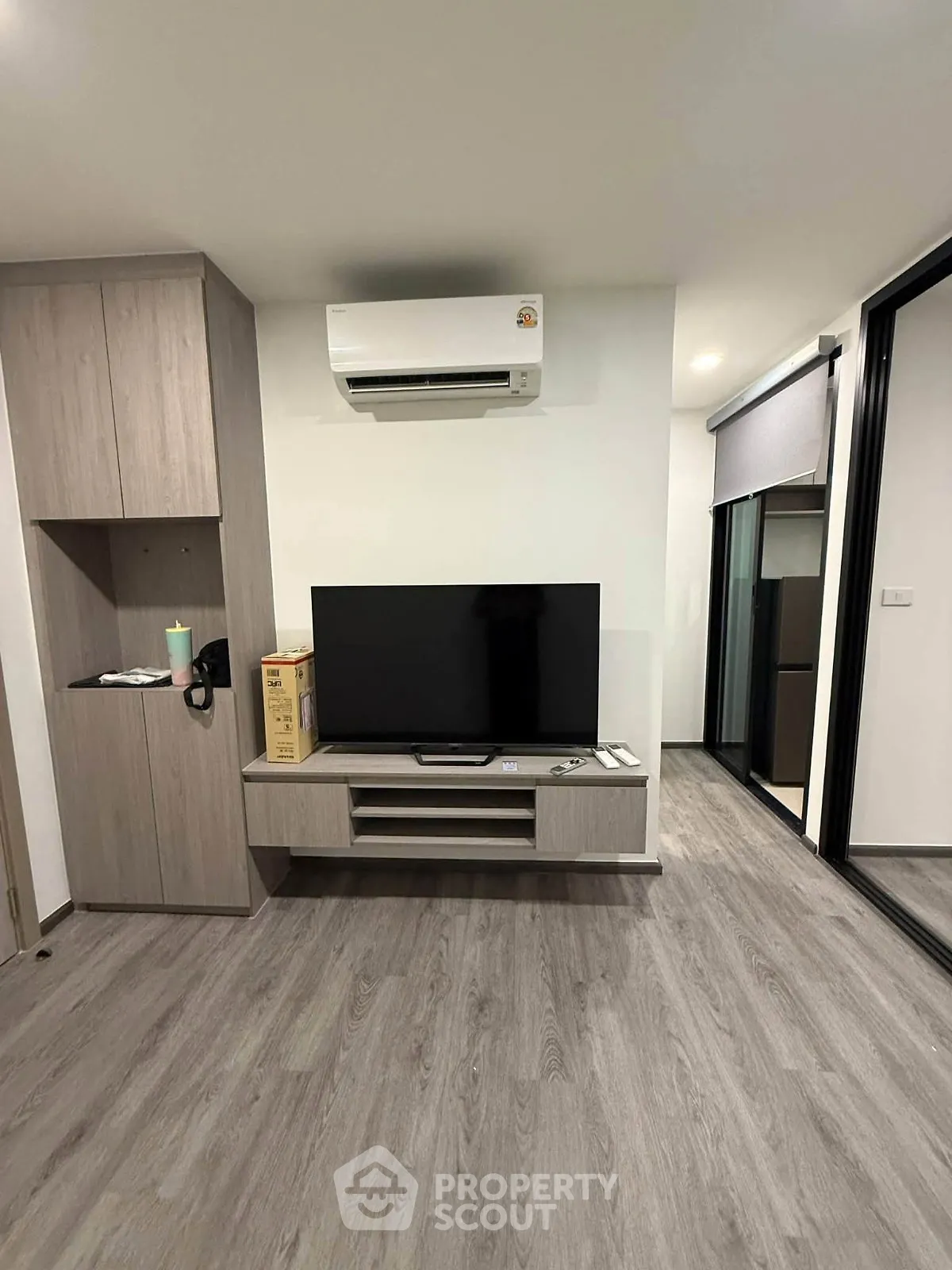 Modern living room with sleek TV setup and air conditioning in stylish apartment.