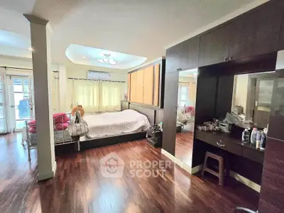 Spacious bedroom with elegant wooden flooring and ample natural light