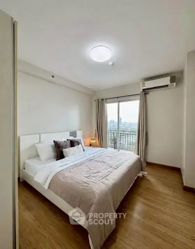 Spacious bedroom with modern decor and city view balcony in a high-rise apartment.