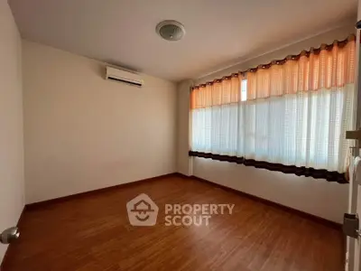 Spacious empty room with wooden flooring and large windows