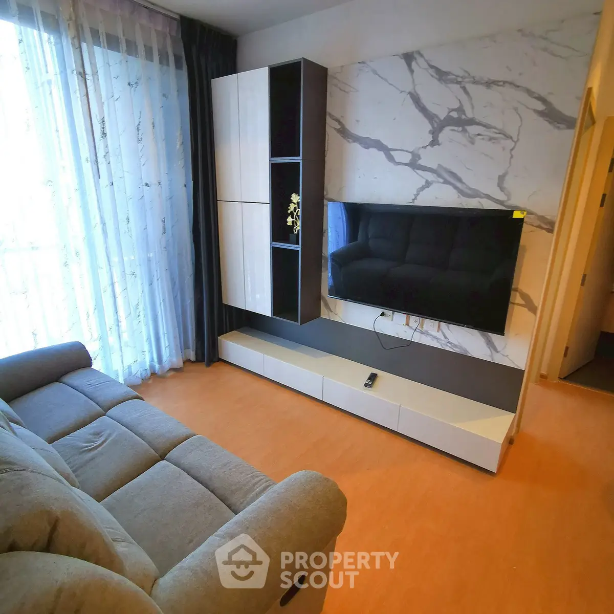 Modern living room with sleek TV setup and stylish marble accent wall.
