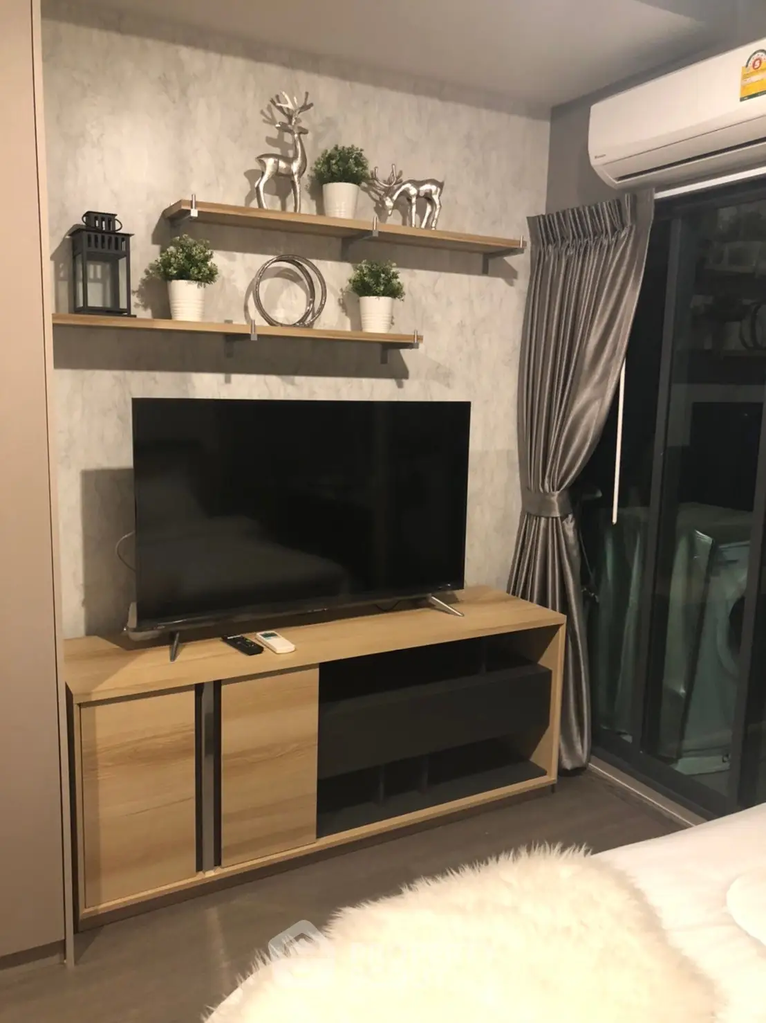 Modern living room with sleek TV stand, decorative shelves, and cozy ambiance.