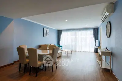 Spacious living room with elegant dining area and large windows.