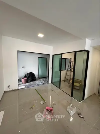 Modern interior under renovation with glass partitions and tiled flooring.