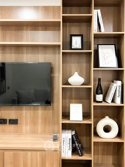 Modern living room with stylish wooden shelving and mounted TV, perfect for contemporary home decor.