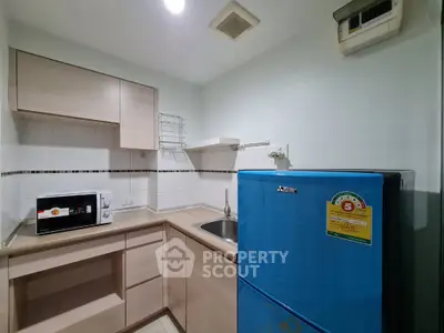 Compact kitchen with blue fridge and microwave in modern apartment
