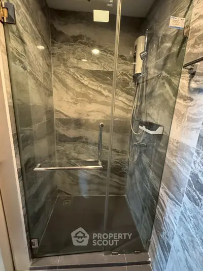 Luxurious marble-tiled shower with glass enclosure and modern fixtures