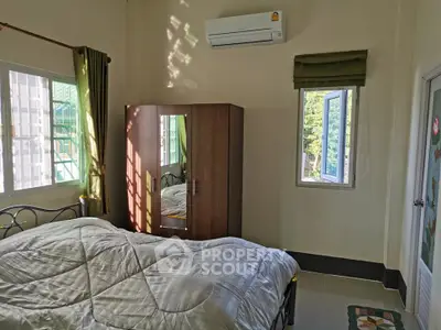 Cozy bedroom with natural light, featuring a mirrored wardrobe and air conditioning.