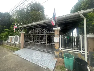 Charming gated entrance with tiled driveway and lush greenery, perfect for privacy and security.