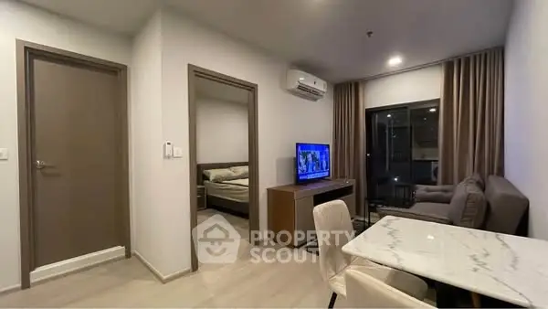 Modern apartment interior with open living room and dining area, featuring sleek furniture and ambient lighting.
