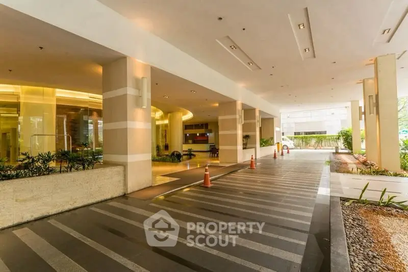 Elegant building entrance with modern design and landscaped surroundings.