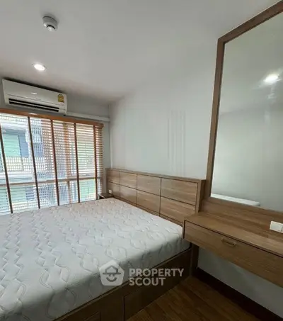 Cozy bedroom with wooden furniture and large window in modern apartment