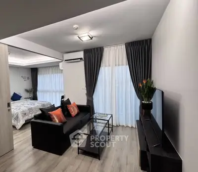 Modern open-plan living room with sleek furniture and large windows in a stylish apartment.